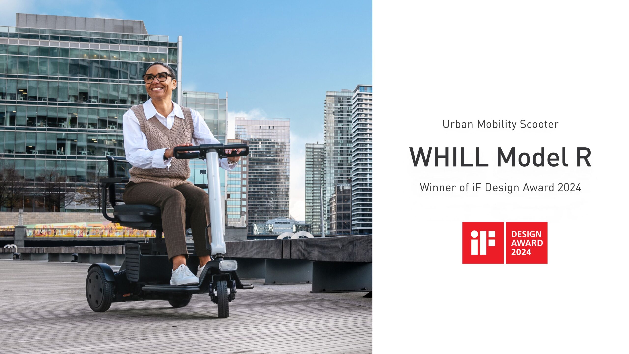 A person joyfully rides a WHILL Model R mobility scooter on a boardwalk, with modern city buildings behind. Text highlights its 2024 iF Design Award win.
